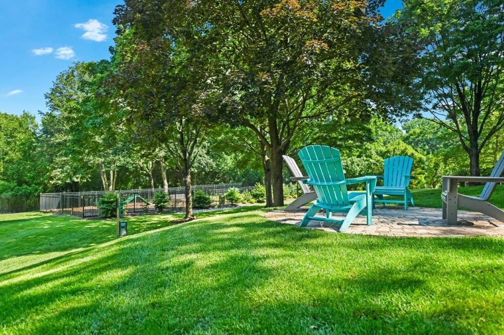 a backyard with two chairs and a picnic table and trees