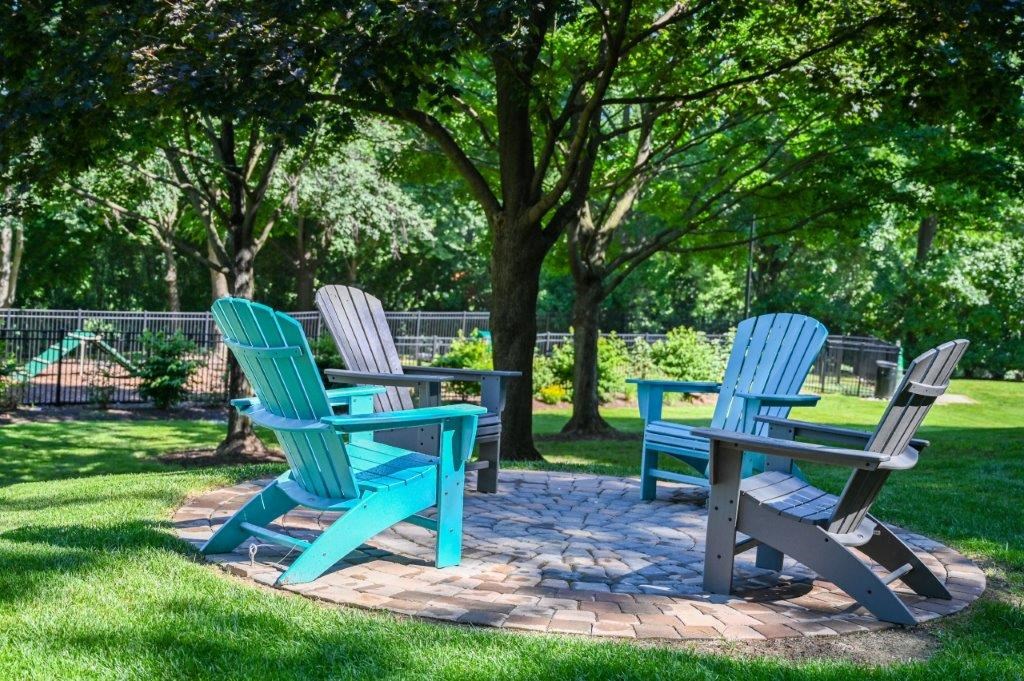 two blue chairs and a table on a brick patio in a park