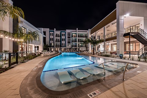 a swimming pool in front of a building at night