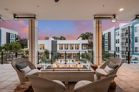 an outdoor patio with a fire pit and chairs