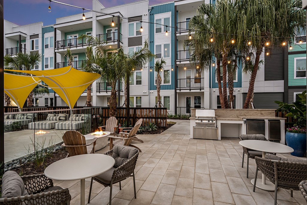 an outdoor patio with tables and chairs in front of an apartment building