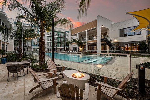 a swimming pool with chairs and a fire pit