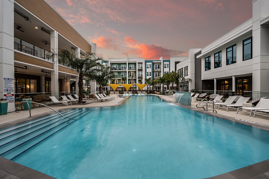 a swimming pool at a hotel with a sunset in the background
