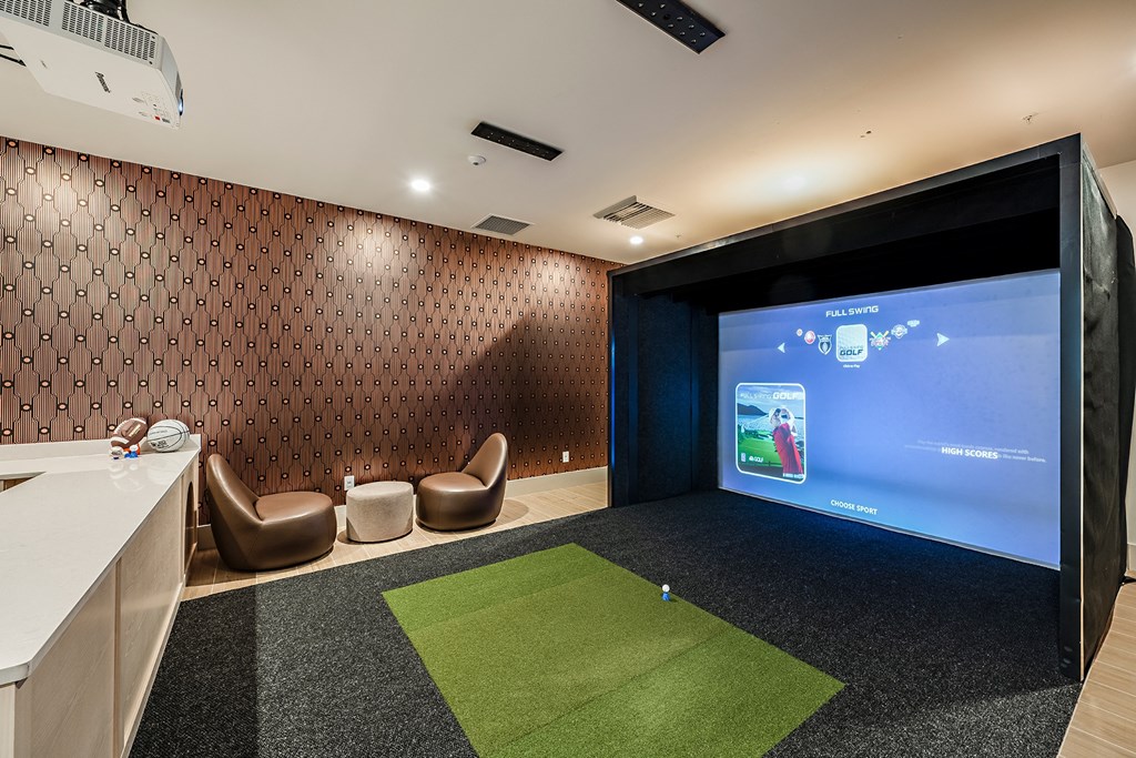 a room with a golf simulator and a large screen on the wall
