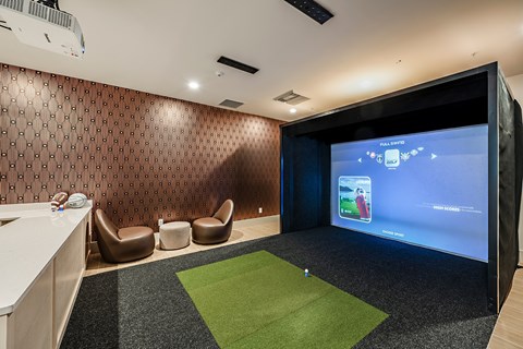 a room with a golf simulator and a large screen on the wall