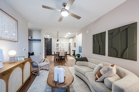 a living room with couches and chairs and a ceiling fan