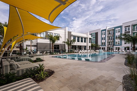 apartments with a pool and lounge chairs in front of a building
