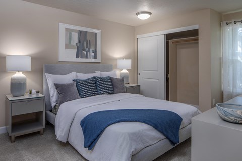 a bedroom with a bed and two nightstands and a door to a bathroom