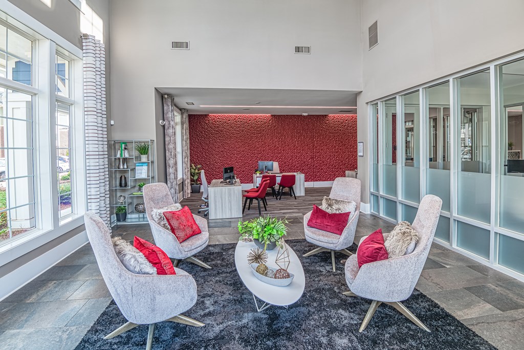 A living room with a red wall and grey chairs.