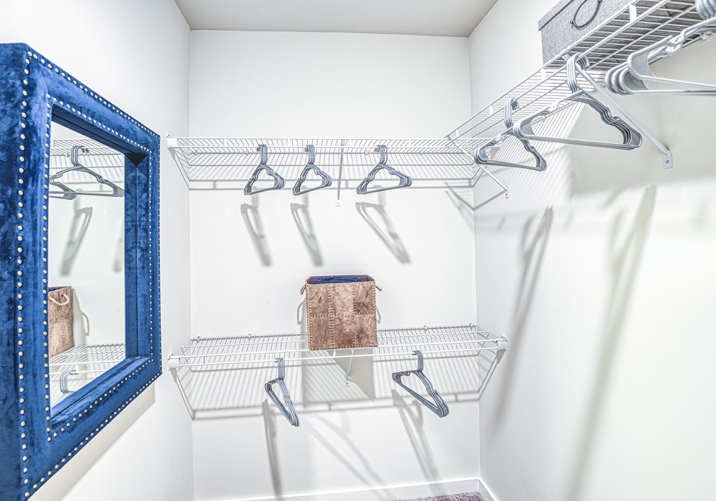 A blue mirror is on the wall next to a wire shelf.