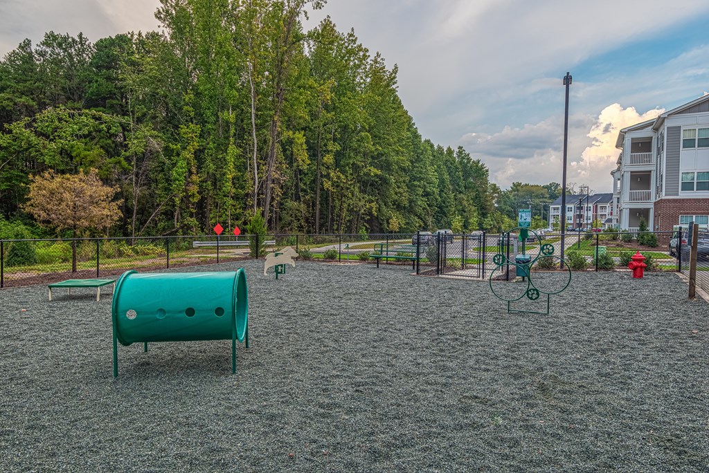 A playground with a green slide and a red fire hydrant.