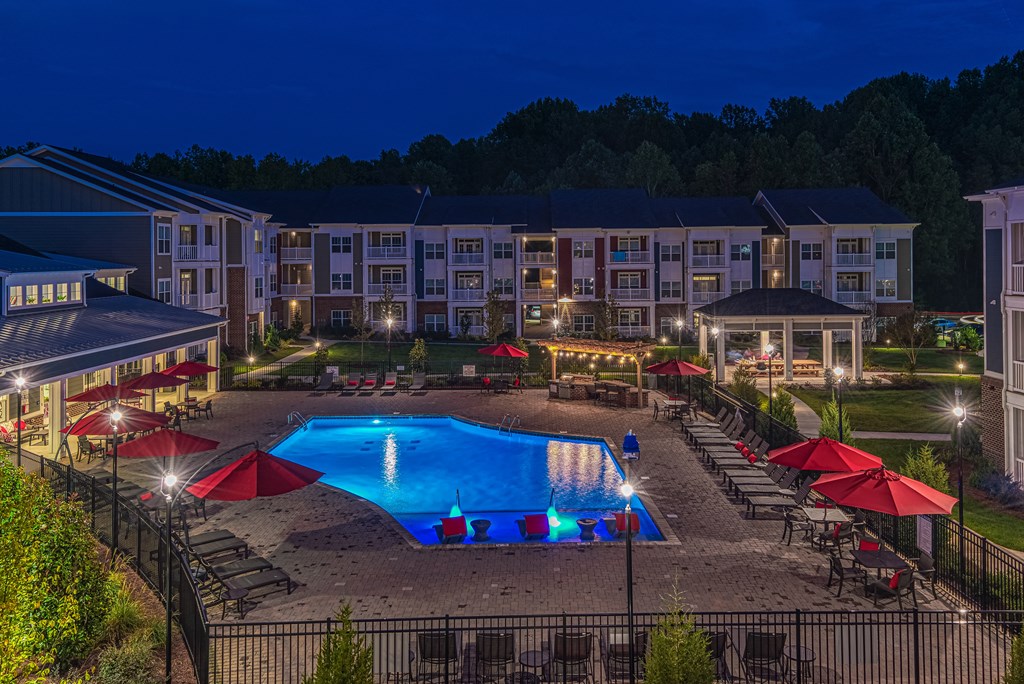 A swimming pool surrounded by red umbrellas and lounge chairs at a resort.