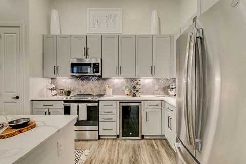 A modern kitchen with a refrigerator on the right and a microwave above the oven.
