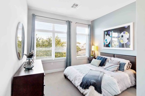 A bedroom with a large bed and a window with blinds.