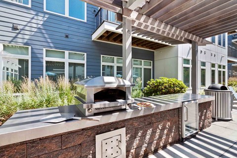 A modern outdoor kitchen with a pizza oven and a trash can.