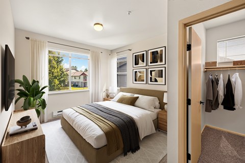 A bedroom with a large bed and a view of a house through the window.
