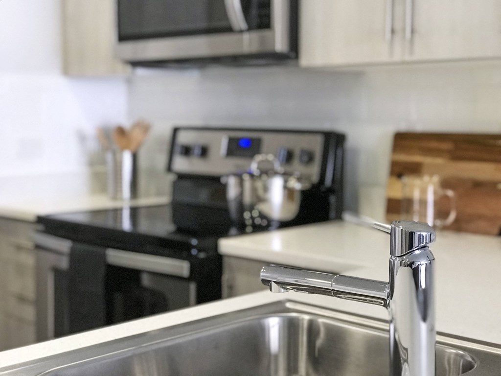 Revetment house modern and spacious kitchen with island and light gray cabinetry.  Stainless steel electric stove top.
