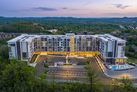 A large, modern building with a parking lot in front and a pool in the middle.