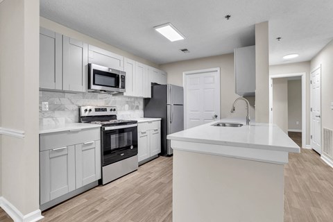 A modern kitchen with a white countertop and stainless steel appliances.