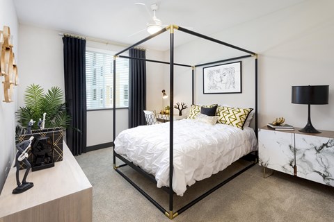 A bedroom with a four-poster bed and a marble side table.