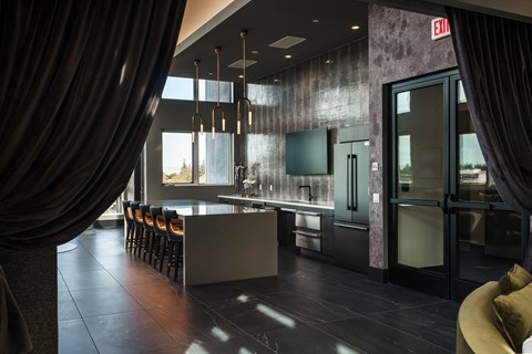 a kitchen with a long counter and chairs and a glass door