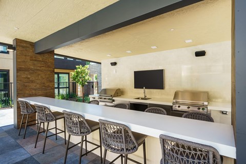 a large kitchen with a long white counter and chairs
