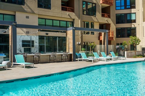 a swimming pool with lounge chairs and a building in the background