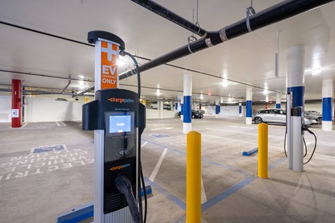 a gas pump in a parking garage with cars in the background