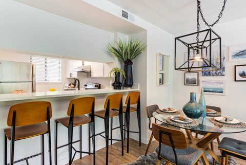 A modern kitchen with a bar area and a dining table set for two.