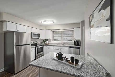 A modern kitchen with a granite countertop and stainless steel appliances.