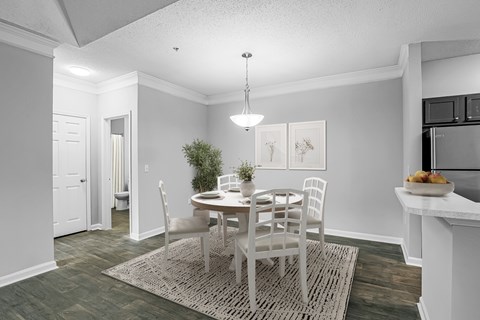 A dining room with a table set for two and a kitchen area in the background.