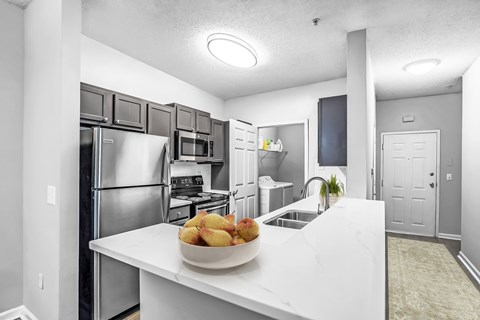 A kitchen with a bowl of fruit on the counter.