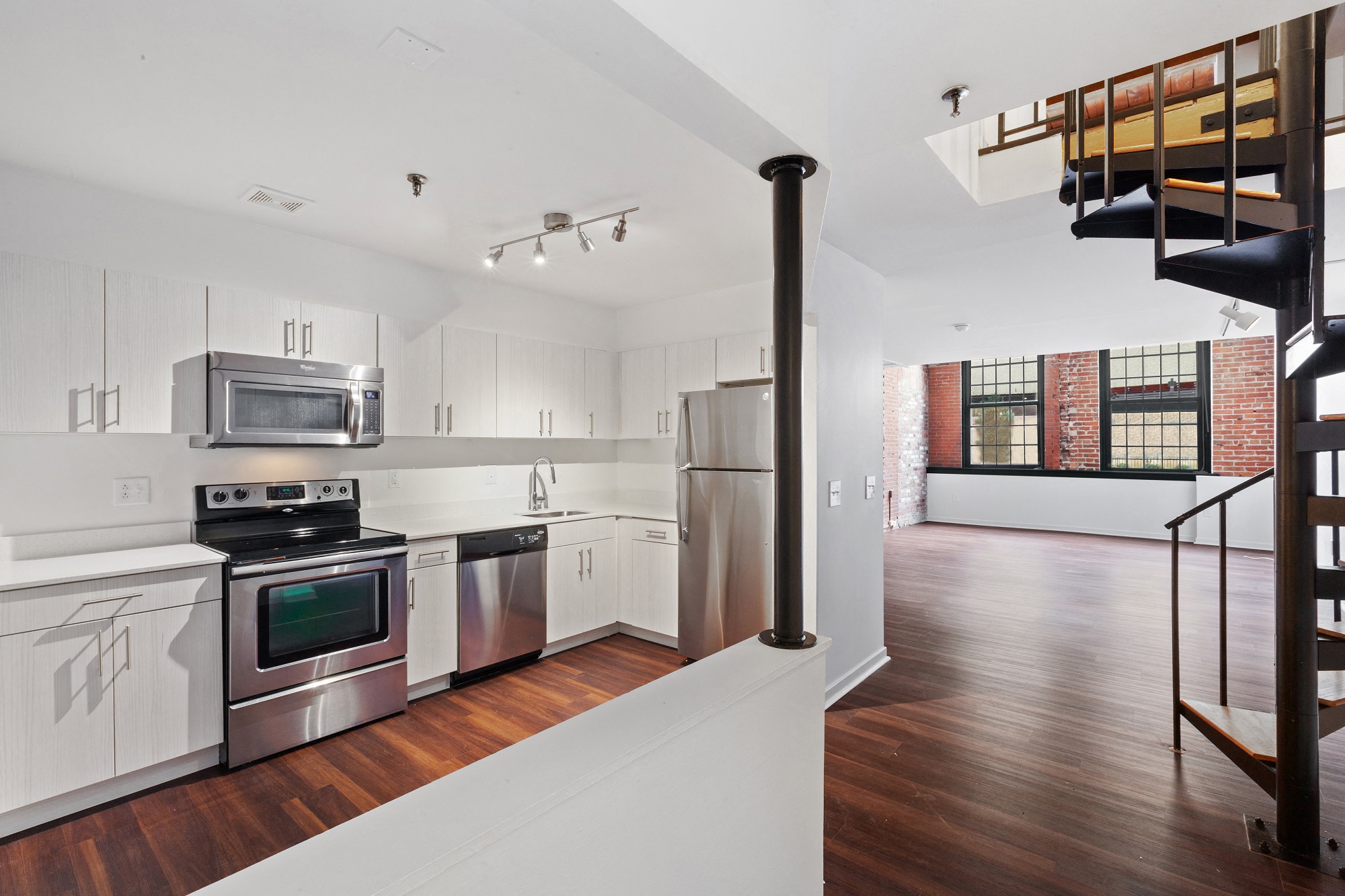 A kitchen with white cabinets and a wood floor.