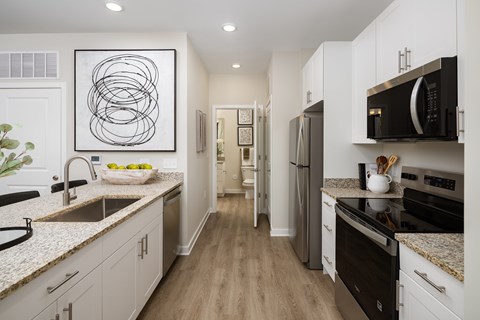A modern kitchen with a white cabinet and black appliances.