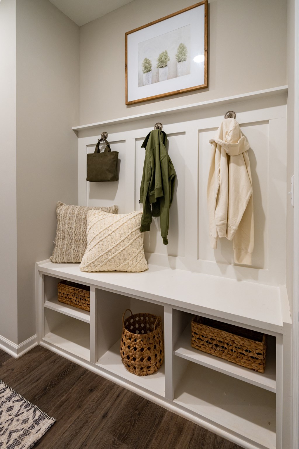 a walk in closet with a bench with pillows and baskets
