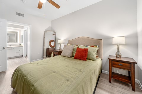 A bedroom with a bed, nightstand, and a ceiling fan.