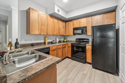 A kitchen with black appliances and wooden cabinets.