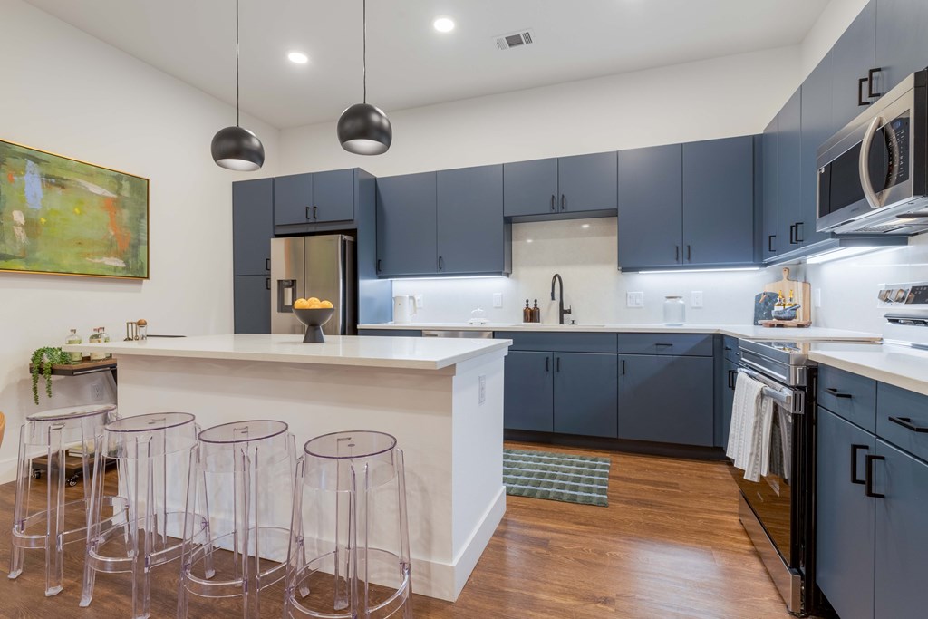 A kitchen with a white counter and purple bar stools.