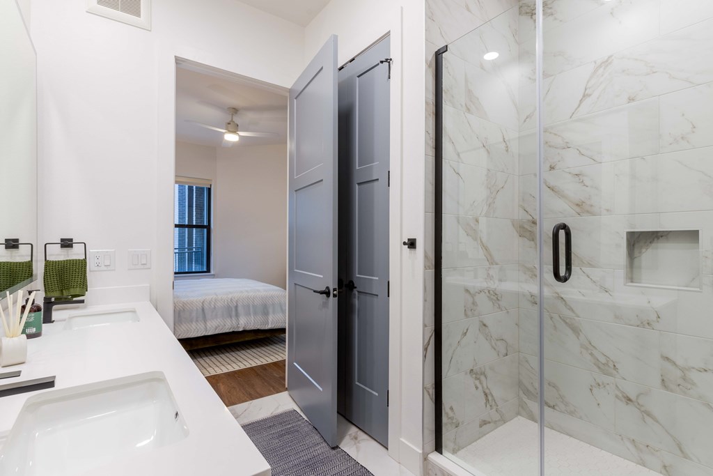 A bathroom with marble tiles and a walk-in shower.