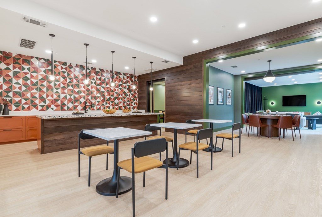 A modern dining area with a wooden floor and a patterned wallpapered backdrop.
