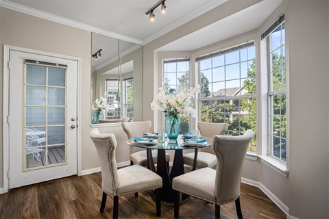 A dining room with a table set for two and a view of the backyard.