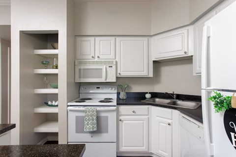 A kitchen with white cabinets and a black countertop.