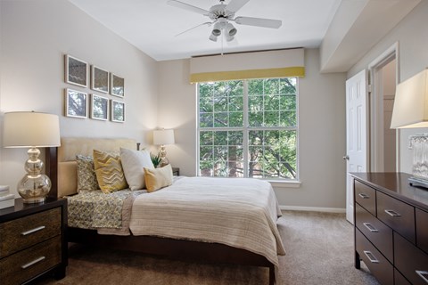 A bedroom with a bed, dresser, and ceiling fan.