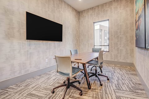 a conference room with a table and chairs and a television on the wall