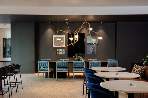 A modern dining area with blue chairs and a long table.