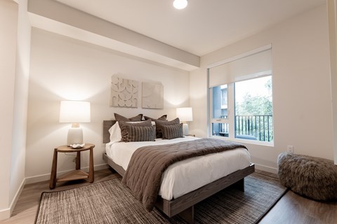 A bedroom with a large bed and a window overlooking a balcony.