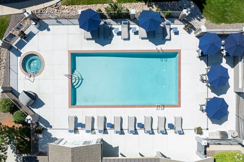 A large swimming pool surrounded by sun loungers and umbrellas.