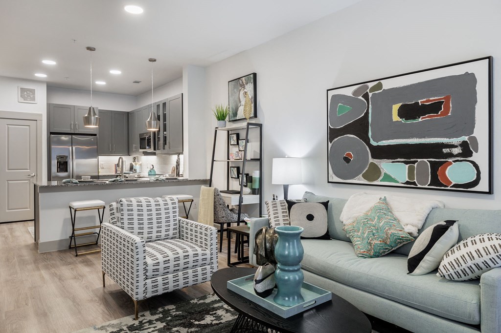 a living room and kitchen with a couch and chairs