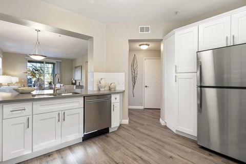 A modern kitchen with white cabinets and a stainless steel refrigerator.