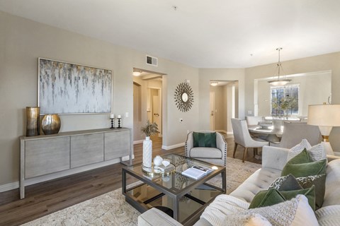 A living room with a glass coffee table and a grey sofa.